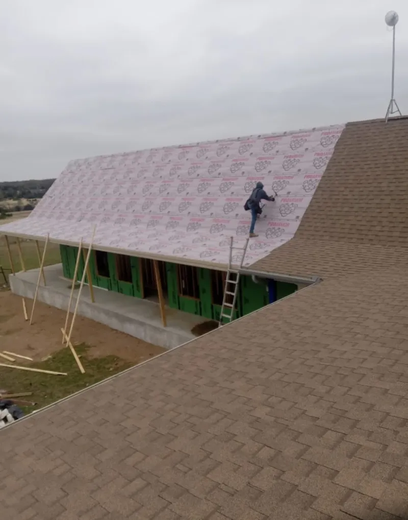 Worker preparing underlayment for a metal roof installation in Rock Falls